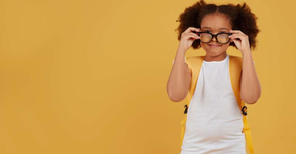 Criança usando óculos, lendo um livro em uma mesa de estudos