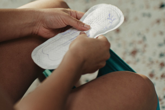 Mulher segurando um produto da TENA para incontinência urinária, apresentando opções de proteção