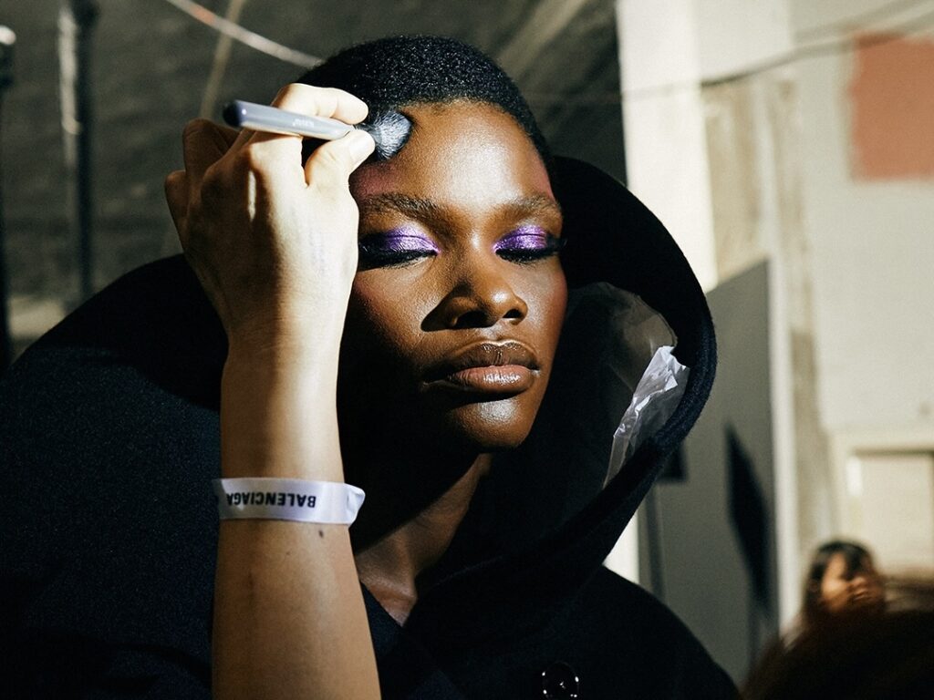 Modelos com maquiagem retrô e futurista na Paris Fashion Week, destacando batons azulados e tiaras zigzag.