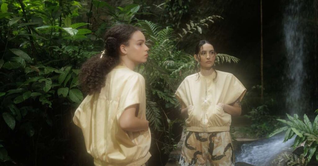 Modelo vestindo peça da coleção Criptídeos da marca Souedo, destacando elementos da cultura amazônica em um cenário urbano